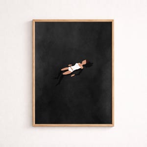 May include: A framed wall art print featuring a minimalist illustration of a figure floating in a dark, textured black void. The figure is depicted in a white two-piece swimsuit, with dark hair and skin tones, positioned centrally against the deep black background.