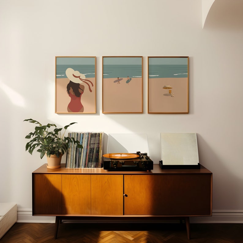 May include: Three framed illustrations of a woman in a swimsuit and hat, two people surfing, and a beach umbrella on a beach.