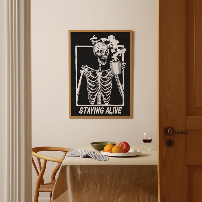 May include: Black and white illustration of a skeleton drinking from a mug with steam rising from the mug. The text "STAYING ALIVE" is below the skeleton.