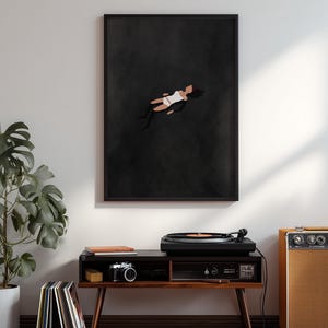 May include: A framed wall art print featuring a minimalist illustration of a figure floating in a dark, solid black void. The figure is depicted in a simplified style, wearing a white top and white bottoms, with dark hair against the black background.