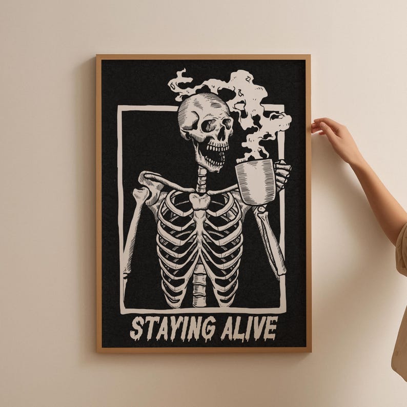 May include: Black and white illustration of a skeleton holding a steaming cup of coffee. The text "STAYING ALIVE" is below the skeleton.