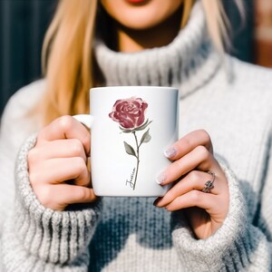 May include: White ceramic mug with a watercolor illustration of a single pink rose and the name "Jessica" written in cursive.