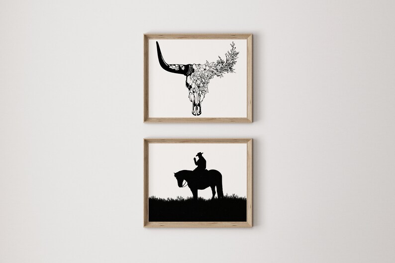 May include: Two framed black and white illustrations. The top illustration is a bull skull with flowers growing out of it. The bottom illustration is a silhouette of a person riding a horse.