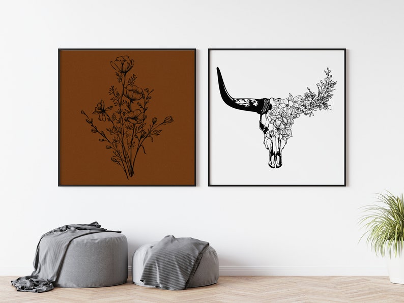 May include: Two black and white framed prints. The print on the left features a bouquet of flowers on a brown background. The print on the right features a bull skull with flowers on a white background.