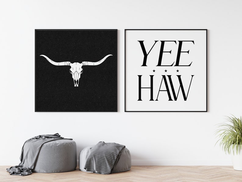 May include: Two black framed prints on a white wall. The print on the left features a white bull skull on a black background. The print on the right features the text "YEE HAW" in black on a white background.