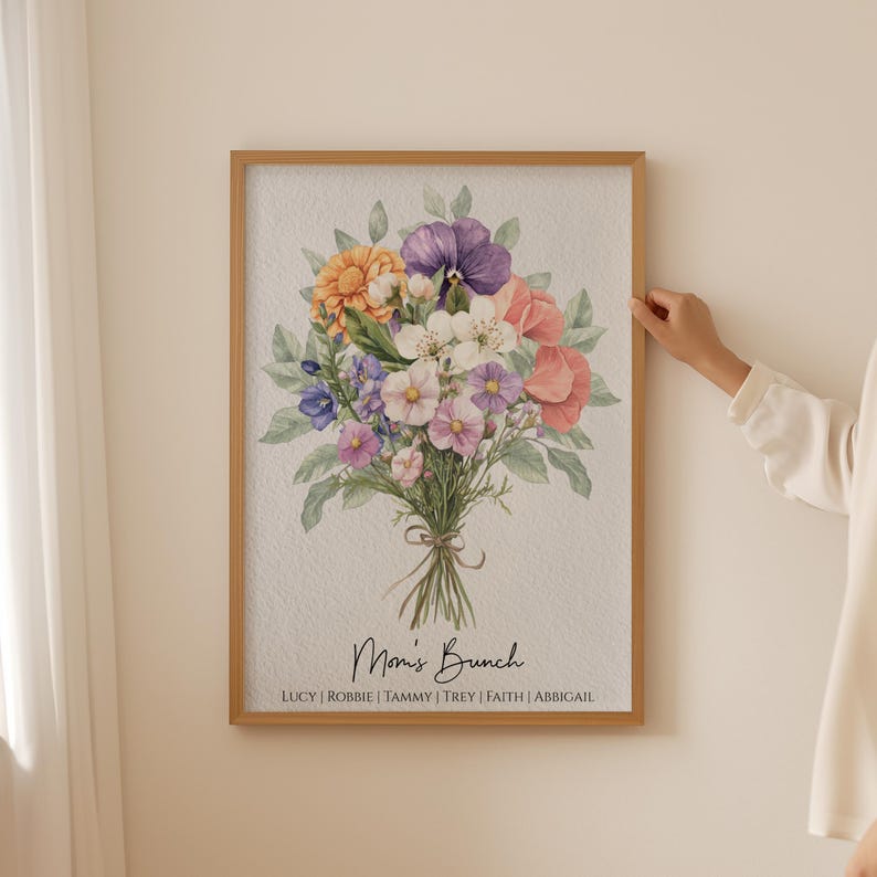 May include: A framed watercolor print of a bouquet of flowers in shades of pink, purple, and yellow. The flowers are arranged in a vase and the print is titled "Mom's Brunch" with the names Lucy, Robbie, Tammy, Trey, Faith, and Abbigail listed below.