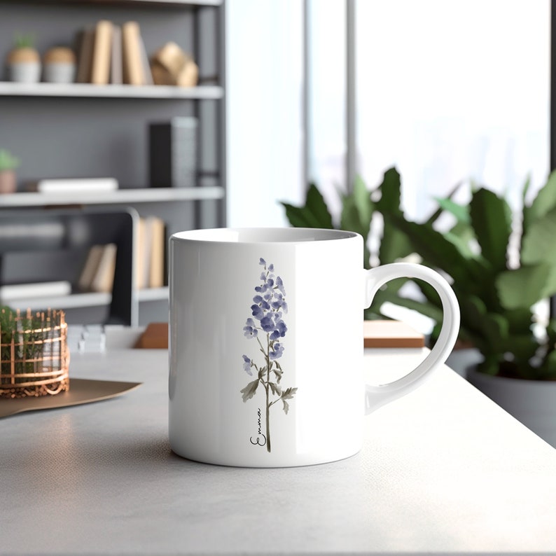 May include: White ceramic mug with a watercolor illustration of a purple flower and the word "Emma" in cursive.