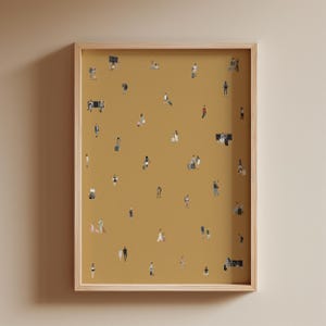 May include: A framed art print featuring a mustard-colored background with numerous tiny figures of people. The figures are dressed in various outfits, suggesting a crowd or gathering. The frame is made of light-colored wood.