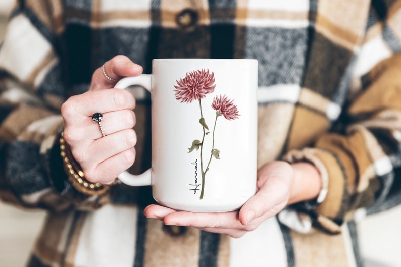 May include: White ceramic mug with a watercolor illustration of pink flowers and the word "Hamaki" in cursive.