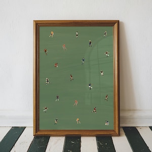 May include: A framed print showing a soccer match in progress. The image has many small figures in different coloured kits on a green pitch. The frame is a warm brown, set against a white wall and a black and white striped floor.