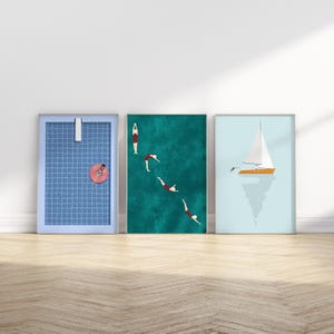 K&ouml;nnte beinhalten: Drei gerahmte Drucke mit einem Sommerthema. Der erste Druck zeigt einen blauen gekachelten Pool mit einer Person, die auf einem rosa aufblasbaren Ring schwimmt. Der zweite Druck zeigt ein t&uuml;rkisfarbenes Meer mit vier Personen, die ins Wasser springen. Der dritte Druck zeigt ein wei&szlig;es Segelboot auf einem hellblauen Meer.