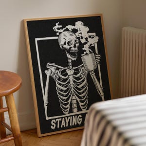 May include: Black and white illustration of a skeleton holding a steaming mug with the text "STAYING ALIVE".