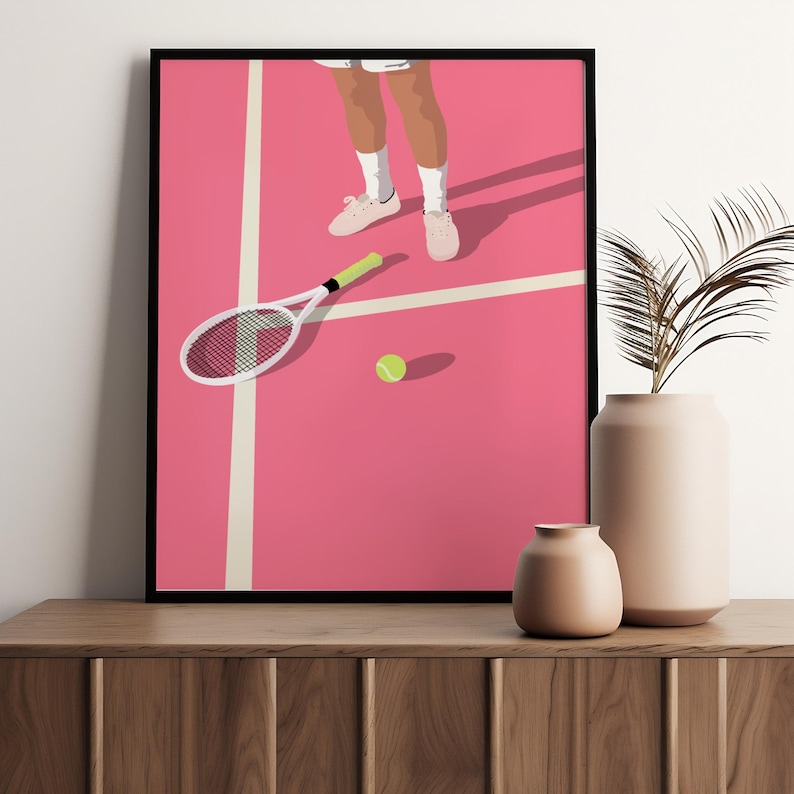 May include: A pink tennis court with a white tennis racket lying on the ground and a yellow tennis ball. A person's legs and feet are visible in the top of the image.