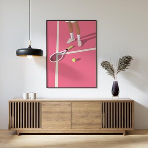 May include: A pink tennis court with a white line and a tennis racket lying on the court. A tennis ball is on the court. A person's legs and feet are visible in the background.