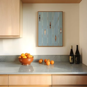 May include: A kitchen counter with a bowl of oranges, two bottles of wine, and a framed print of swimmers in a pool.