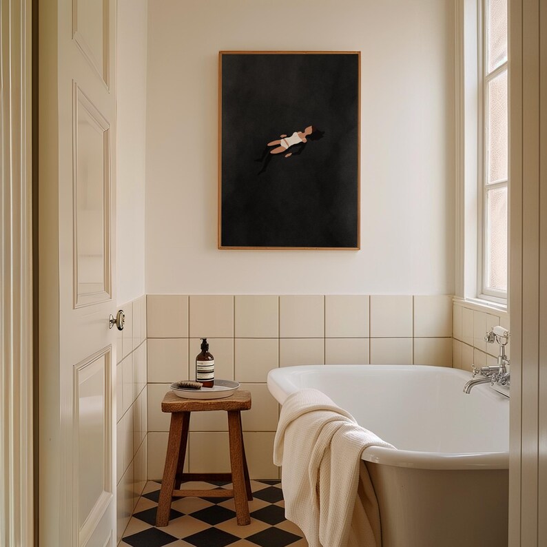 May include: A rectangular wall art print in a wooden frame featuring a dark charcoal background with a small, stylized figure floating in the center. The figure wears a white swimsuit and has dark hair, depicted in a minimalist, flat graphic style.