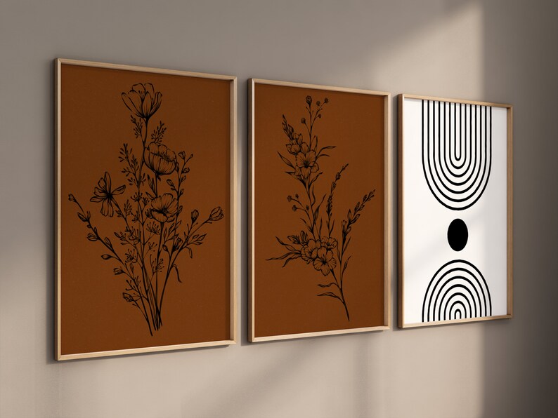 May include: Three framed prints with a minimalist aesthetic. The left and centre prints feature black line drawings of flowers on a brown background. The right print features a black and white geometric design with a circle and curved lines.