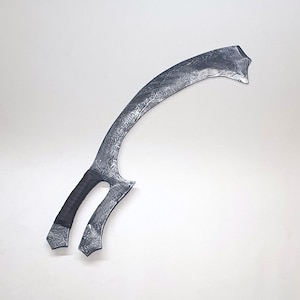 May include: A silver-colored curved sword with a black handle. The sword has a unique design with a pointed tip and a curved blade.