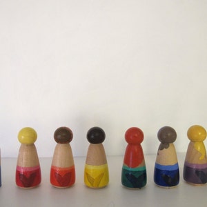 May include: Ten wooden peg dolls, each painted in a different color, with a different design on the bottom. The colors are white, yellow, brown, dark brown, red, dark blue, light blue, purple, and pink.