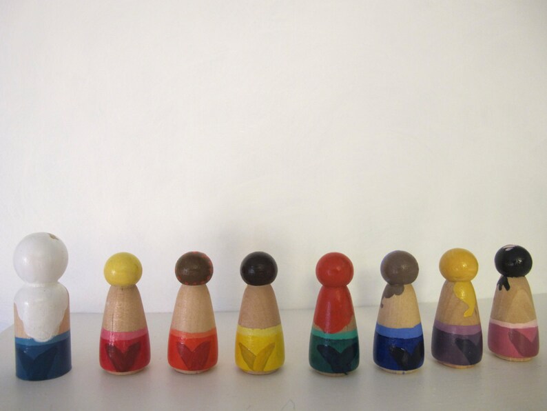 May include: Ten wooden peg dolls, each painted in a different color, with a different design on the bottom. The colors are white, yellow, brown, dark brown, red, dark blue, light blue, purple, and pink.