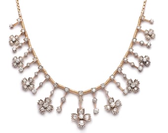 May include: A delicate gold necklace featuring a floral design. The necklace is crafted from a fine gold chain adorned with sparkling diamonds. The diamonds are arranged in a pattern of flowers, each with a central diamond surrounded by smaller diamonds.