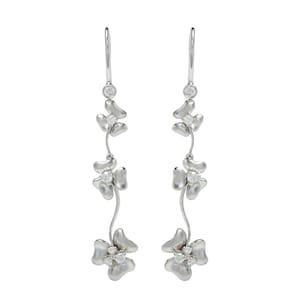May include: Silver dangle earrings with three flower-shaped charms, each with a small clear stone in the center.
