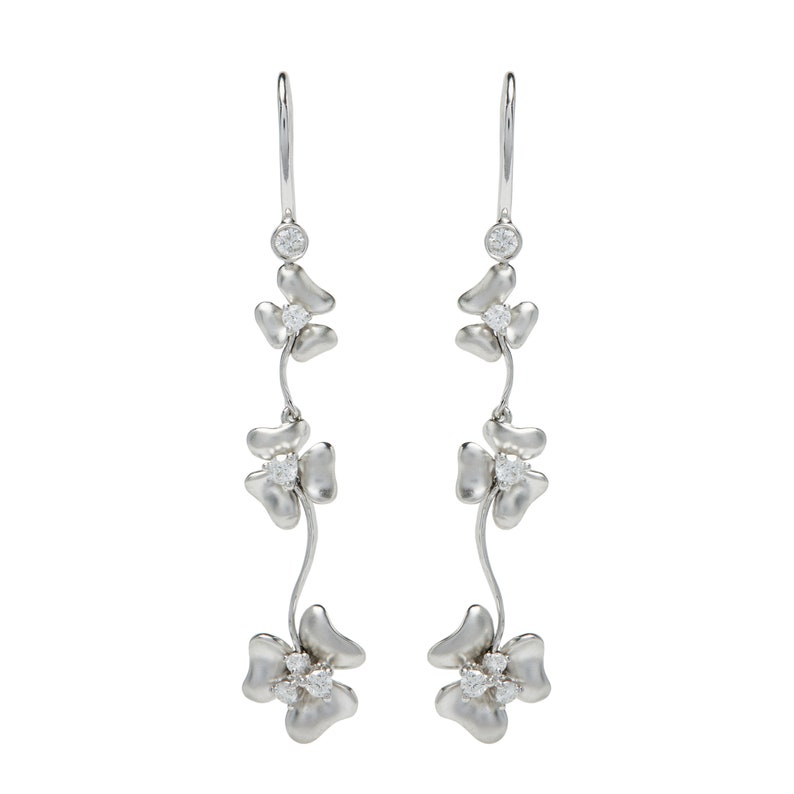 May include: Silver dangle earrings with three clover-shaped charms, each with a small clear diamond in the center.