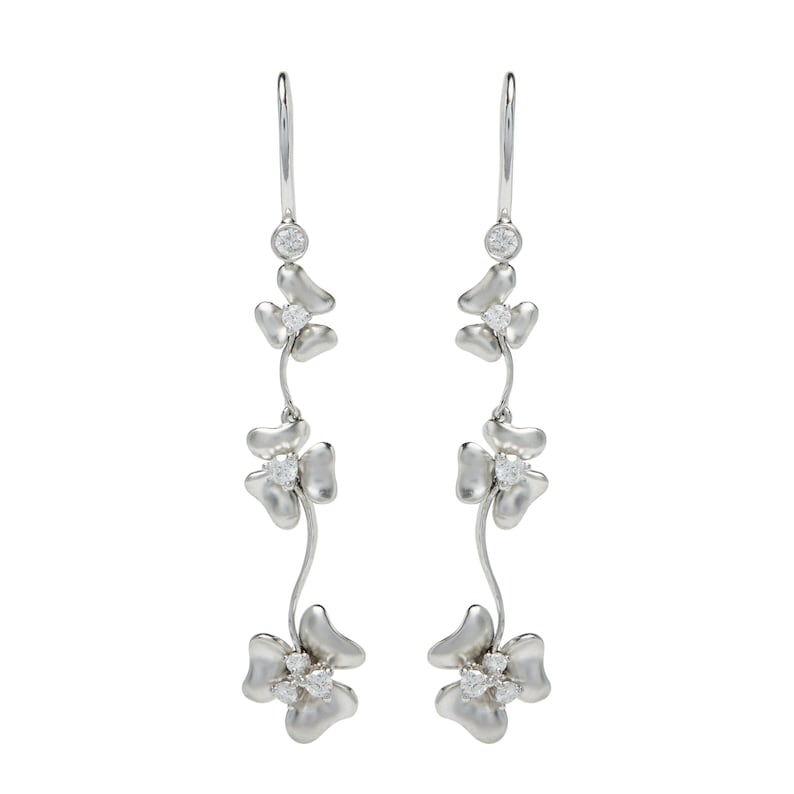 May include: Silver dangle earrings with three flower-shaped charms, each with a small clear stone in the center.