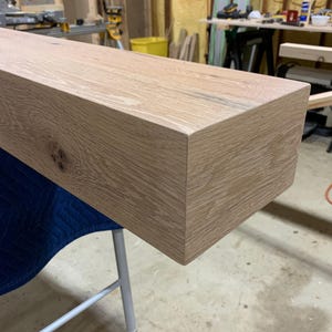 May include: A close-up of a light brown wooden shelf, showing the grain of the wood and the smooth, finished edges.