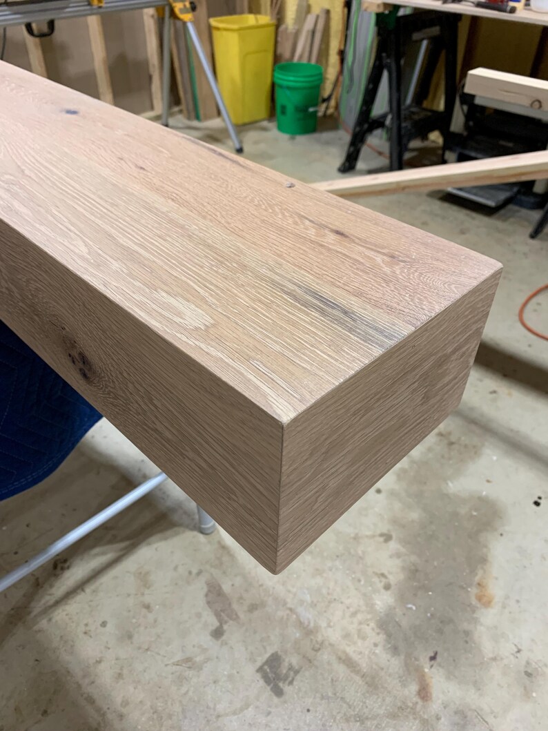 May include: A close-up of a light-colored wooden shelf with a smooth, slightly textured surface. The shelf has a rectangular shape with rounded edges and is made of natural wood.