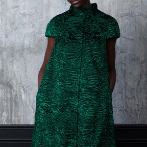 May include: A short-sleeved, knee-length dress in a vibrant emerald green. The dress features a high, rounded collar and a textured, patterned fabric. The garment is buttoned down the front and has a tailored fit.