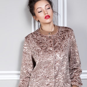 Puede incluir: Chaqueta bomber texturizada marr&oacute;n y beige con cuello redondo y cierre de botones. La chaqueta tiene dobladillo y pu&ntilde;os de canal&eacute;. La modelo lleva pintalabios rojo.