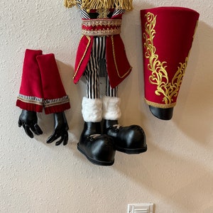 May include: A red and black striped costume with gold trim and a matching hat, gloves, and boots. The costume is made of fabric and has a festive, whimsical design.