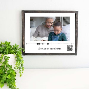 May include: A black framed photo with a picture of an older woman and a young girl. The photo has a sound wave graphic and the text "forever in our hearts".