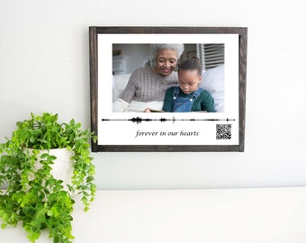 May include: A black framed photo with a picture of an older woman and a young girl. The photo has a sound wave graphic and the text "forever in our hearts".
