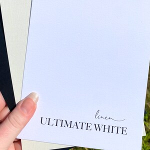 May include: Two white cardstock samples, one with a linen texture and the other smooth. The smooth sample has the text "linen ULTIMATE WHITE" printed on it.
