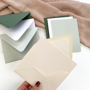 Powder pink blank card and envelope set held in hand. A2 size - 4 1/4 x 5 1/2 inches.
