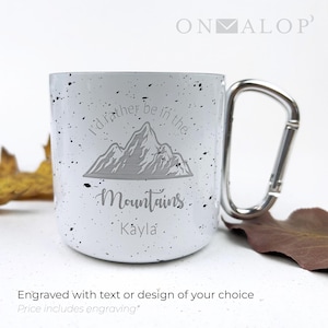 May include: White speckled enamel mug with a silver carabiner handle. The mug features an engraved mountain design and the words "I'd rather be in the Mountains" and "Kayla". The text "Engraved with text or design of your choice" is at the bottom.