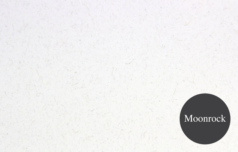 May include: A white textured background with a black circle in the bottom right corner. The circle contains the text "Moonrock" in white.