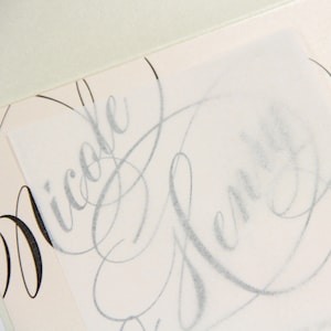 May include: A close-up of a wedding invitation with the names "Nicole" and "Jeremy" written in cursive script.