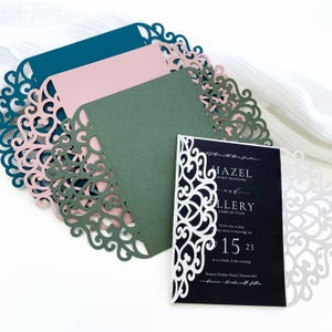 Puede incluir: Una colección de fundas para invitaciones cortadas con láser en azul verdoso, rosa empolvado y verde oliva, junto a una funda blanca con una tarjeta de invitación negra con texto blanco que dice Hazel Marie Swofford y Ellery James Hutton.