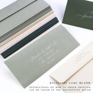 May include: A stack of rectangular envelopes in shades of sage green, blush pink, and dark navy blue. One sage green envelope features white calligraphy text reading Alexander & Isabel Lee, 12 Wilton Circle, Old Saybrook, Connecticut 06475.