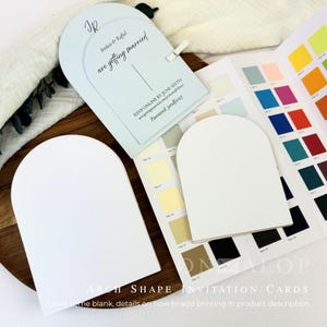 May include: Arch-shaped invitation cards in white and light blue. The light blue card features black text reading 'JR', 'Jessica & Rafiel are getting married', 'RSVP ONLINE BY JUNE SIXTH', and 'Password: jandf2027'. A color swatch booklet is included.