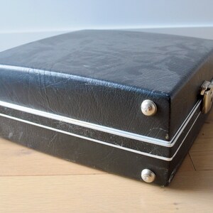 May include: A black vinyl carrying case with silver trim and metal clasps. The case has several silver rivets around the edges.