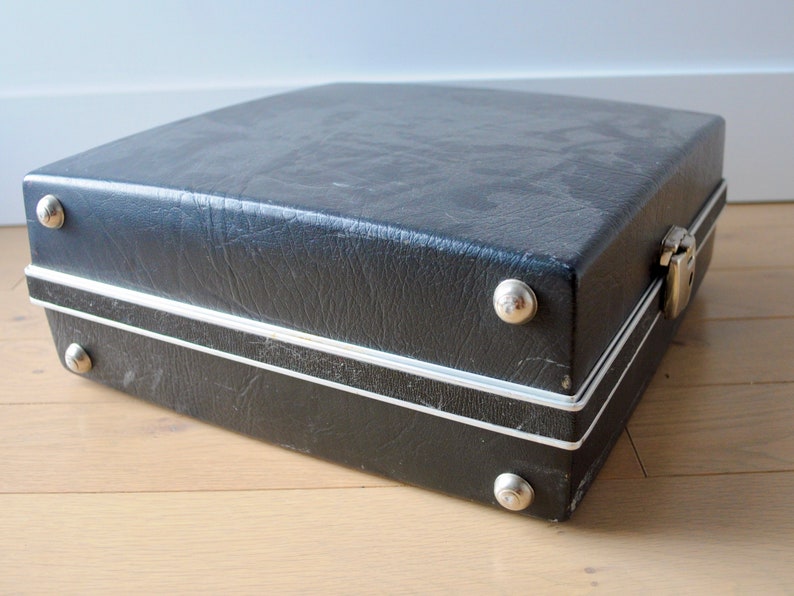 May include: A black vinyl carrying case with silver trim and metal clasps. The case has several silver rivets around the edges.