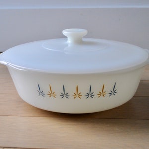 May include: White casserole dish with a lid, featuring a blue and gold starburst design.