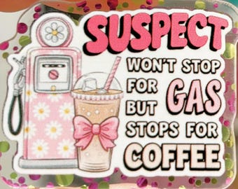 Puede incluir: Un pin acrílico transparente y brillante con las palabras "SUSPECT WON'T STOP FOR GAS BUT STOPS FOR COFFEE" en rosa y blanco. El pin presenta una gasolinera rosa y una taza de café con un lazo rosa.