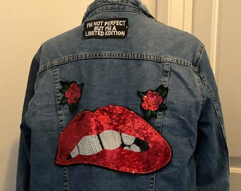 May include: A blue denim jacket with a red sequined lips patch, two red rose patches, and a black patch that says "I'm not perfect but I'm a limited edition".