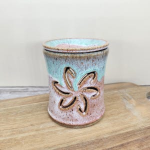 May include: A white ceramic mug with a black handle and the text "But first, coffee" in a handwritten style. The mug is on a white surface. The mug is approximately 4 inches tall.