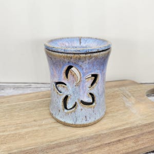 May include: A set of three ceramic mugs with a speckled, matte finish. The mugs are in shades of cream, light gray, and dark gray. Each mug has a simple, minimalist design and a rounded handle.